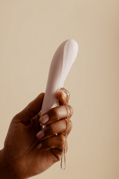 Woman's hand holding a lubricated sex toy for self-pleasure