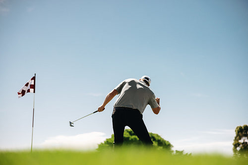 Male golfer celebrating a triumphant moment near a flagstick