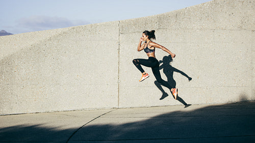 Athletic woman running and jumping outdoors