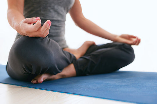 Woman in Lotus pose on exercise mat at gym
