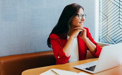 Businesswoman in red blazer working at her laptop in an office setting