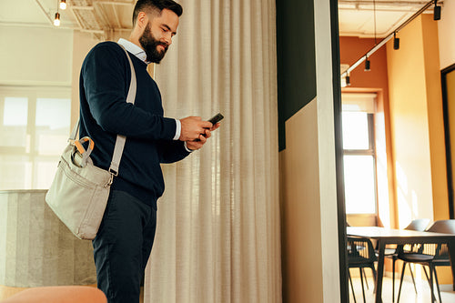 Cheerful businessman using a smartphone in a co-working space