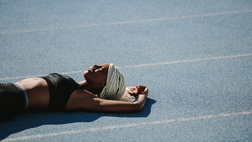 Female sprinter lying on running track after workout