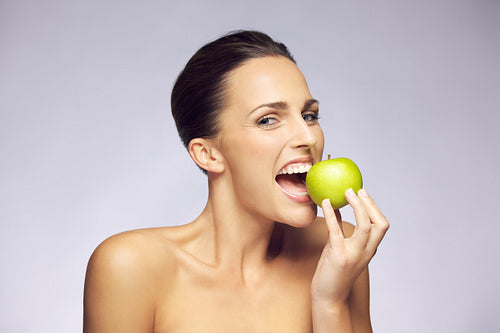 Lovely brunette woman eating fresh green apple