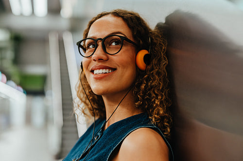 Young woman listens to music in an urban transit station