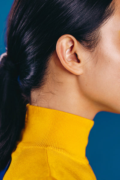 Sideview of a female with flawless skin standing in a studio