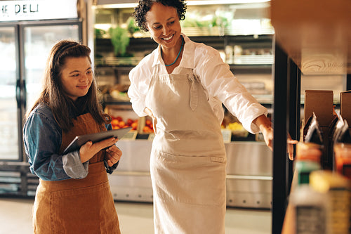 Friendly shop owner training her new employee in a grocery store
