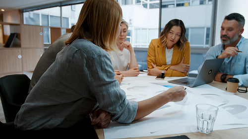Business people collaborating on a project: Group of design architects brainstorming on a set of blueprints