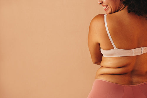 Rearview of a happy plus size woman wearing underwear in a studio