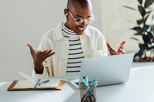 Young woman with glasses having an engaging video conversation on laptop in a bright office