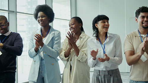 Diverse group of business professionals happily clapping and smiling during a conference or event