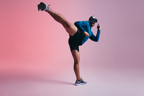 Active young man throwing a kick in virtual reality