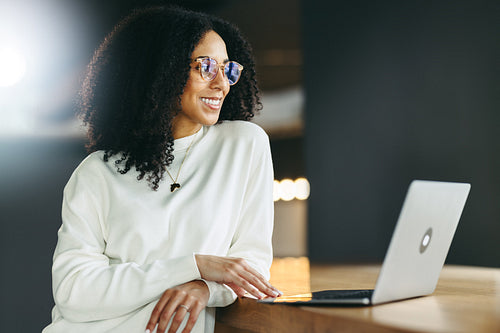Happy young businesswoman looking away thoughtfully in an office