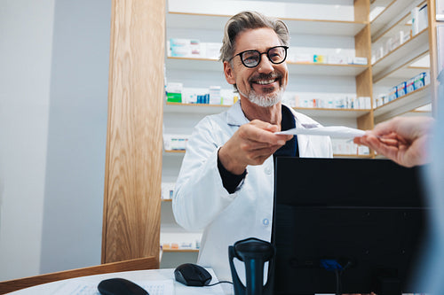 Pharmacist receiving a prescription from a patient in a drug store