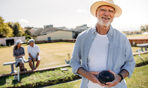 Close up of a man playing boules in a lawn