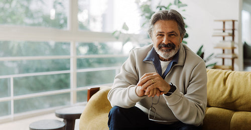 Seated senior man looks toward camera from a sofa
