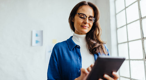 Focused business woman working from a digital tablet in her office