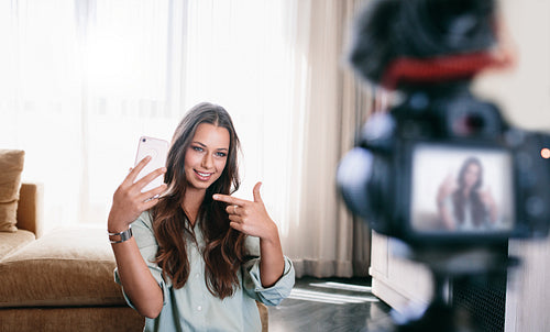 Young woman recording her video on camera mounted on tripod.