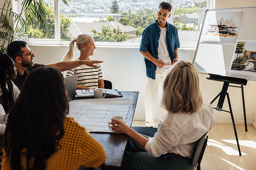 Architects presenting housing designs to colleagues during creative meeting in office