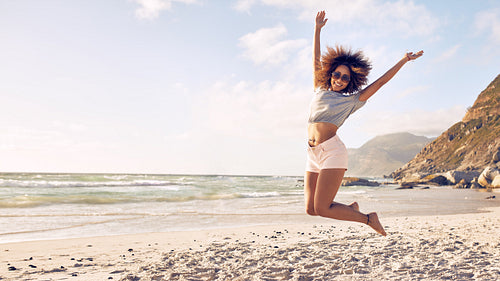 Beautiful young woman jumping at the beach