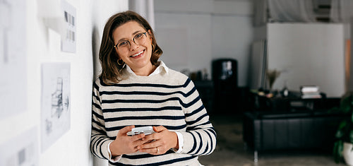 The woman takes a work break with her phone in a design studio beside wall drawings