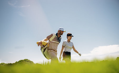 Asian female golfer walking with male companion on golf course