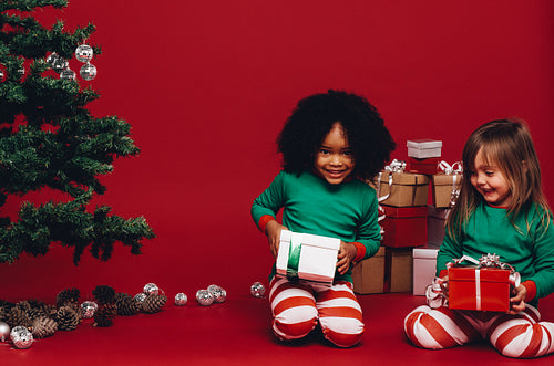 Two kids sitting with their christmas gifts