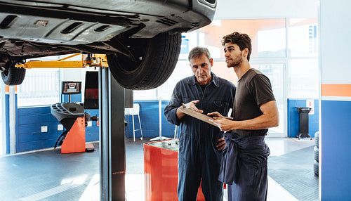 Auto mechanics making a list of repairs on car in service station