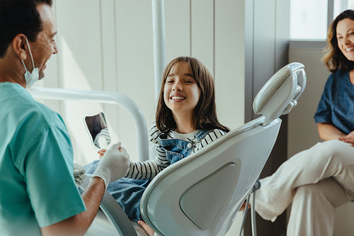 Child patient smiles through family dental checkup with dentist