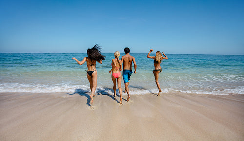 Group of friends running into sea water