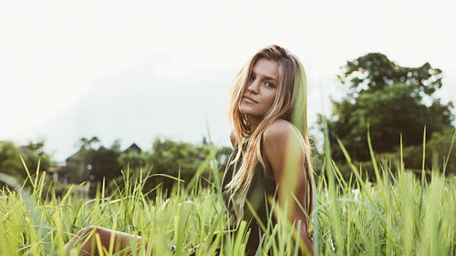 Cute young female model sitting in the meadow