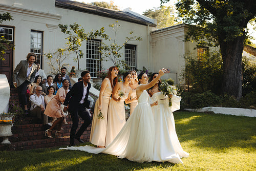 Two brides taking a photo with wedding guests in a lush garden celebration