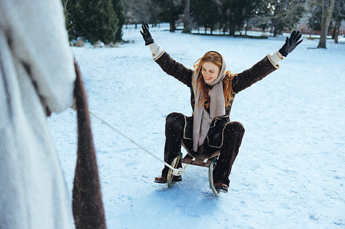Friends pull a woman sledding through snowy park