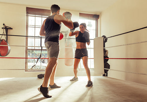 Trainer helping a female boxer with striking techniques