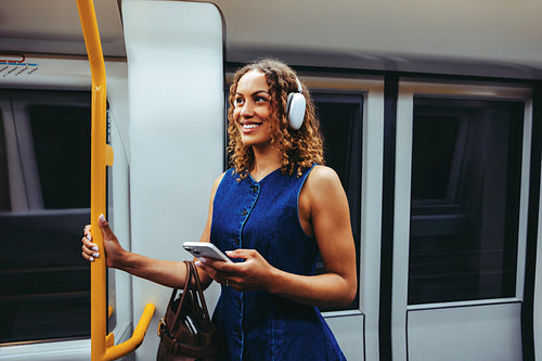 Woman listens to music on subway train using smartphone