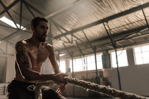 Fitness man pulling rope at gym