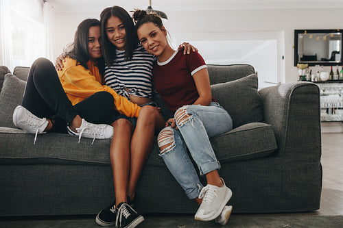 Girl friends sitting on couch holding each other