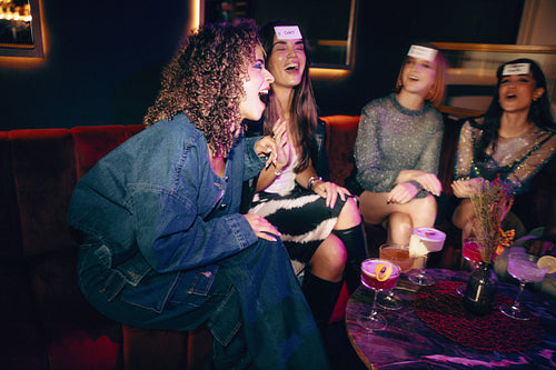 Group of friends laughing and sharing a lively evening with drinks and games