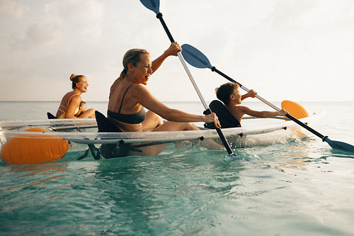 Family enjoying kayaking on a clear sea during a sunny day