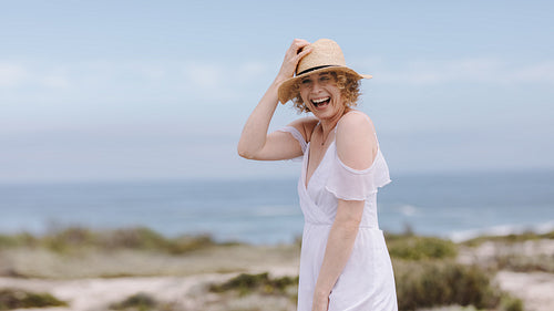 Portrait of a woman standing near sea wearing a hat