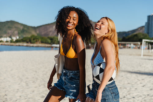 Two joyful friends laughing together on a sunny beach day