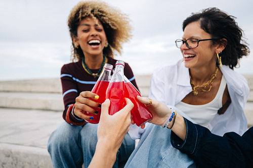 Friends clinking bottles in a candid cheers with beverage