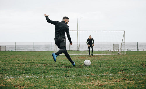 Men playing soccer on field near the sea