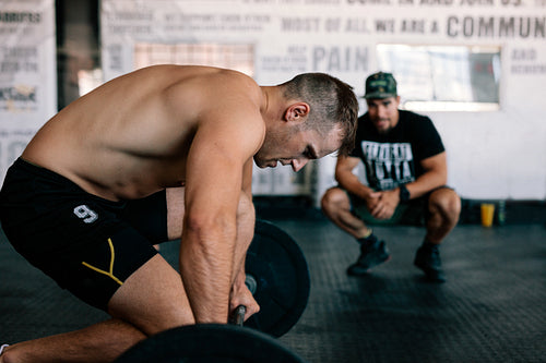 Muscular man lifting a barbell at crossfit gym