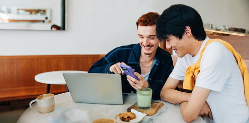 Two friends working together at a café with laptop