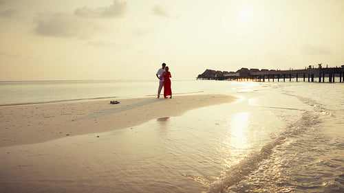 Mature couple embracing on tropical beach at sunset, romantic drone shot
