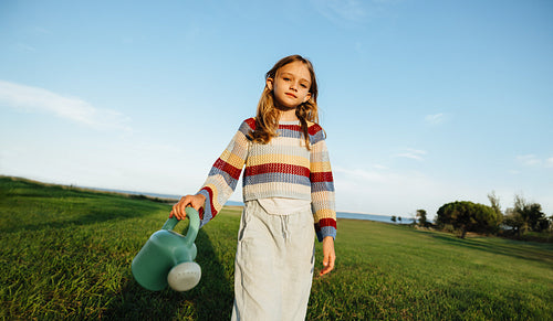Young girl in field with watering can