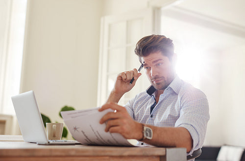 Young man going through paperwork at home office
