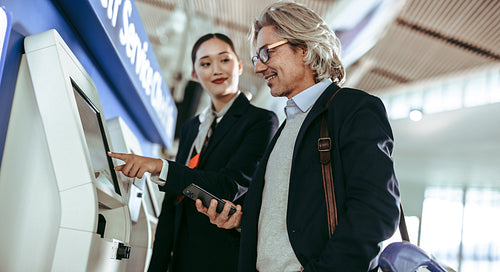 Airport staff helping traveler with self service check-in