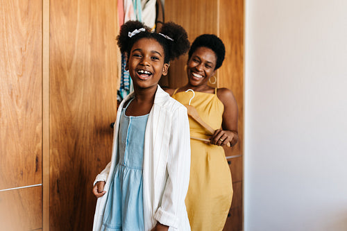 Getting dressed with mom: Little black girl dressing up in her mother's stylish clothing at home